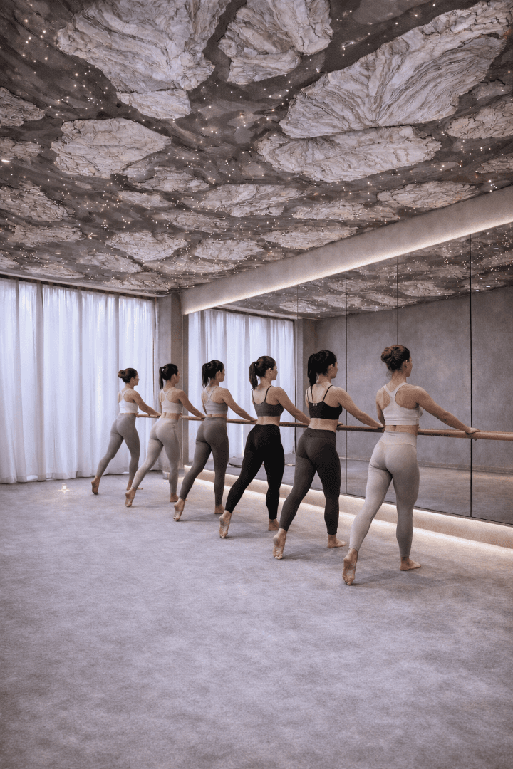 Barre studio bathed in warm light with mirrored arches and barres